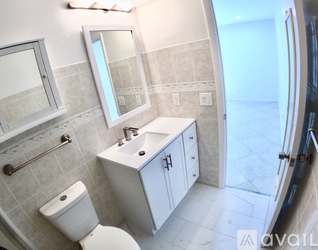A bathroom with a toilet, sink, and mirror.