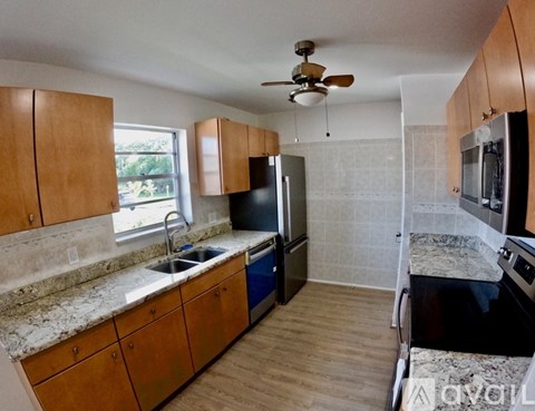 A kitchen with wooden cabinets and a ceiling fan.