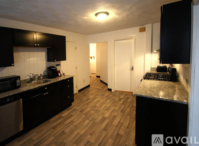 A kitchen with black cabinets and a wooden floor.