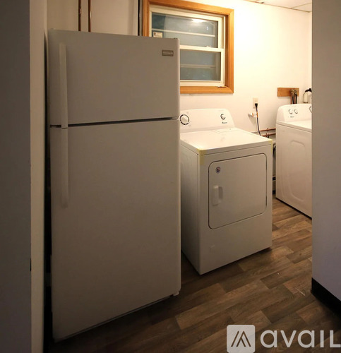 A white refrigerator stands in a room with a washer and dryer.