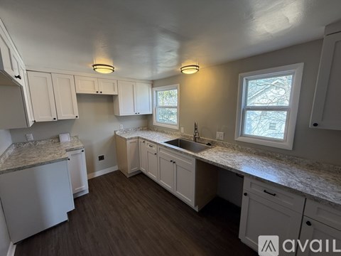 A kitchen with white cabinets and a granite countertop.