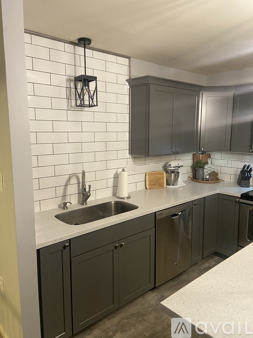 A kitchen with a white tile backsplash and grey cabinets.