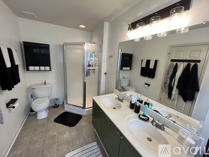 A bathroom with a toilet, sink, mirror, and shower.