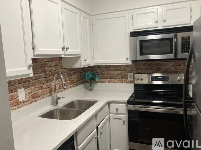A kitchen with white cabinets and a brick backsplash.