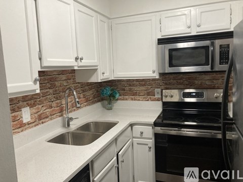 A kitchen with white cabinets and a brick backsplash.