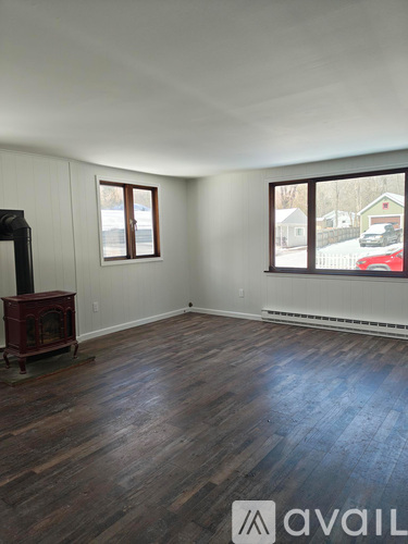 A room with wood flooring and a wood-burning stove.