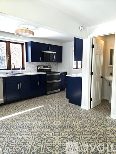 A kitchen with dark blue cabinets and a patterned floor.