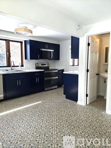 A kitchen with dark blue cabinets and a patterned floor.