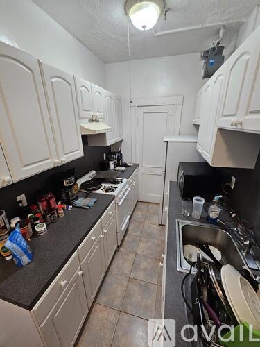 A kitchen with white cabinets and a black counter top.