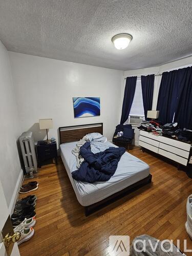 A bedroom with a bed, dresser, and shoes on the floor.