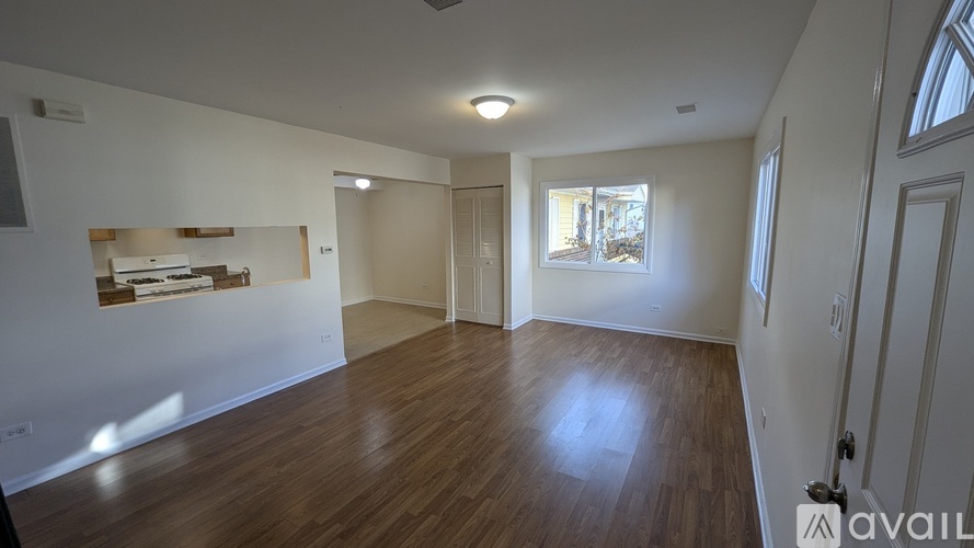 A room with wooden floors and white walls, with a window on the right wall.