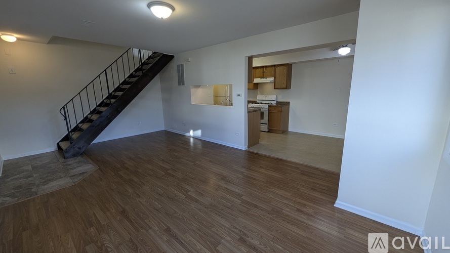 A spacious room with wooden flooring and a staircase leading to another level.