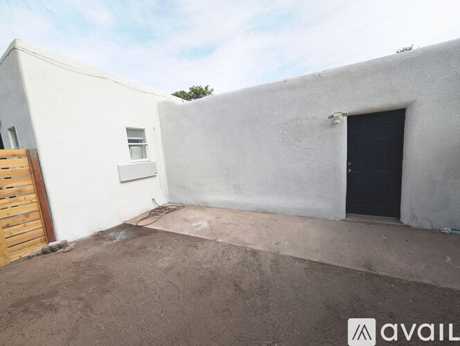 A white building with a black door and a wooden door.
