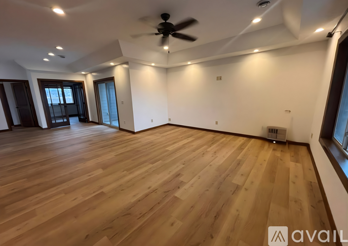 A spacious room with wooden flooring and a ceiling fan.