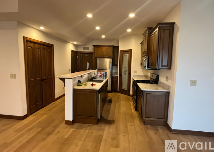 A kitchen with wooden floors and brown cabinets.
