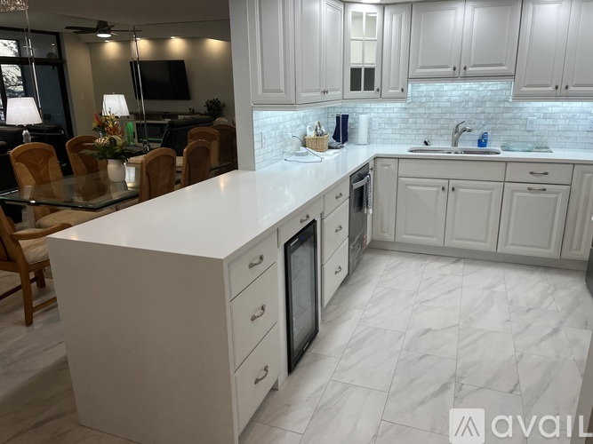 A kitchen with white cabinets and a marble floor.