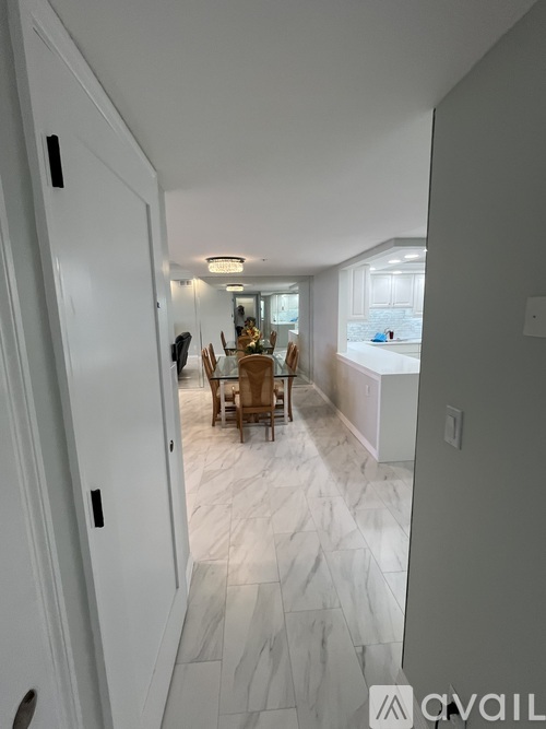 A hallway with a dining area in the background.