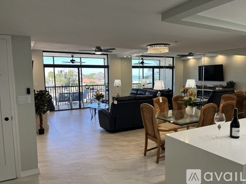 A modern living room with a black sofa and a glass table with a bottle of wine on it.