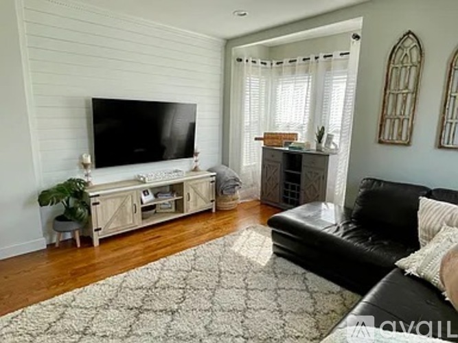A living room with a black couch and a television.