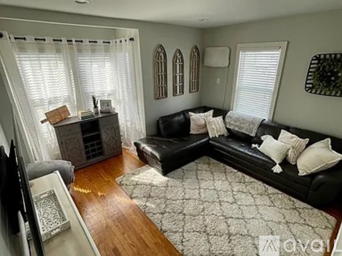 A living room with a black couch and a television.