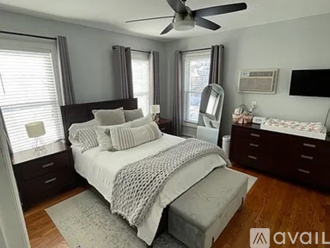 A bedroom with a bed, dresser, and ceiling fan.