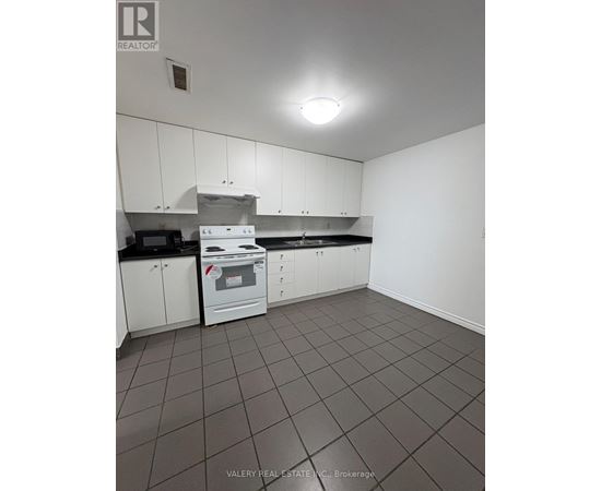 A kitchen with white cabinets and a black counter top.