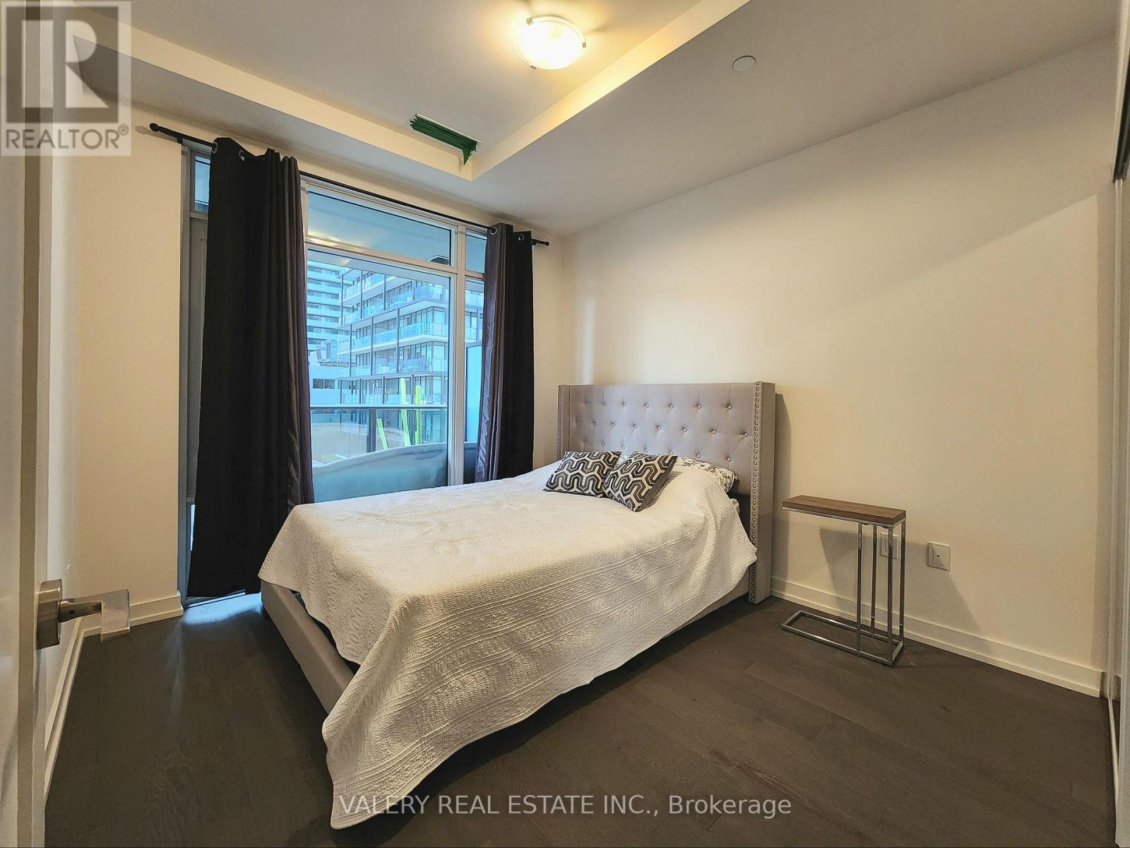 A bedroom with a large bed and a window with black curtains.