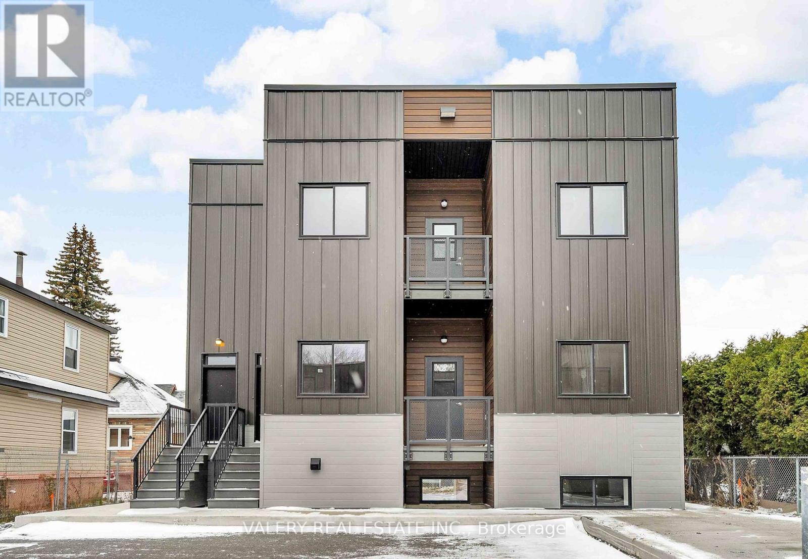 A modern two-story building with a flat roof and a balcony on the second floor.