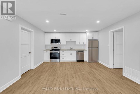 A kitchen with white cabinets and appliances in a white room.