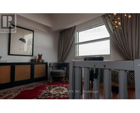 A living room with a grey crib in the foreground and a large window with curtains.