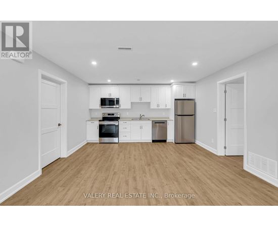 A kitchen with white cabinets and appliances in a white room.
