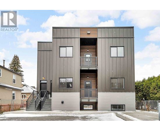 A modern two-story building with a flat roof and a balcony on the second floor.