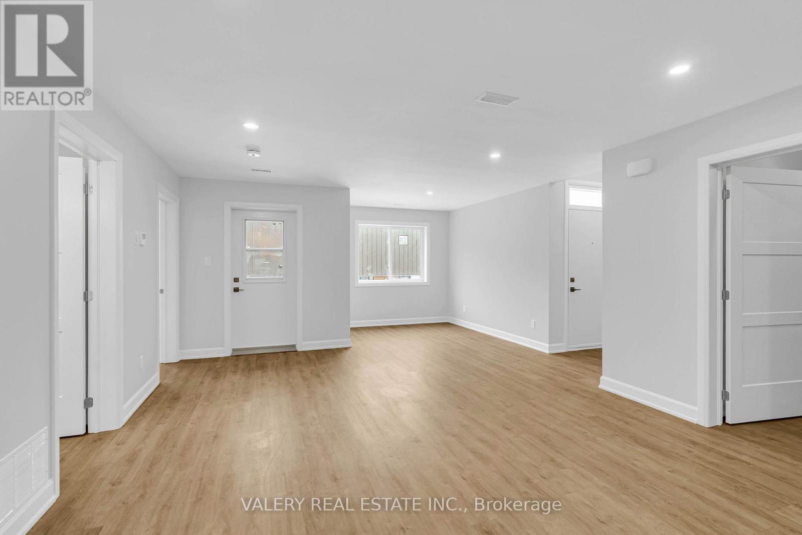 A spacious room with wooden flooring and white walls.
