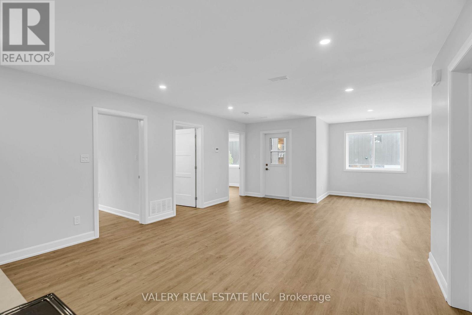 A spacious room with wooden flooring and white walls.
