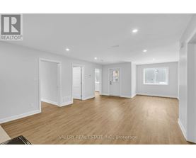 A spacious room with wooden flooring and white walls.