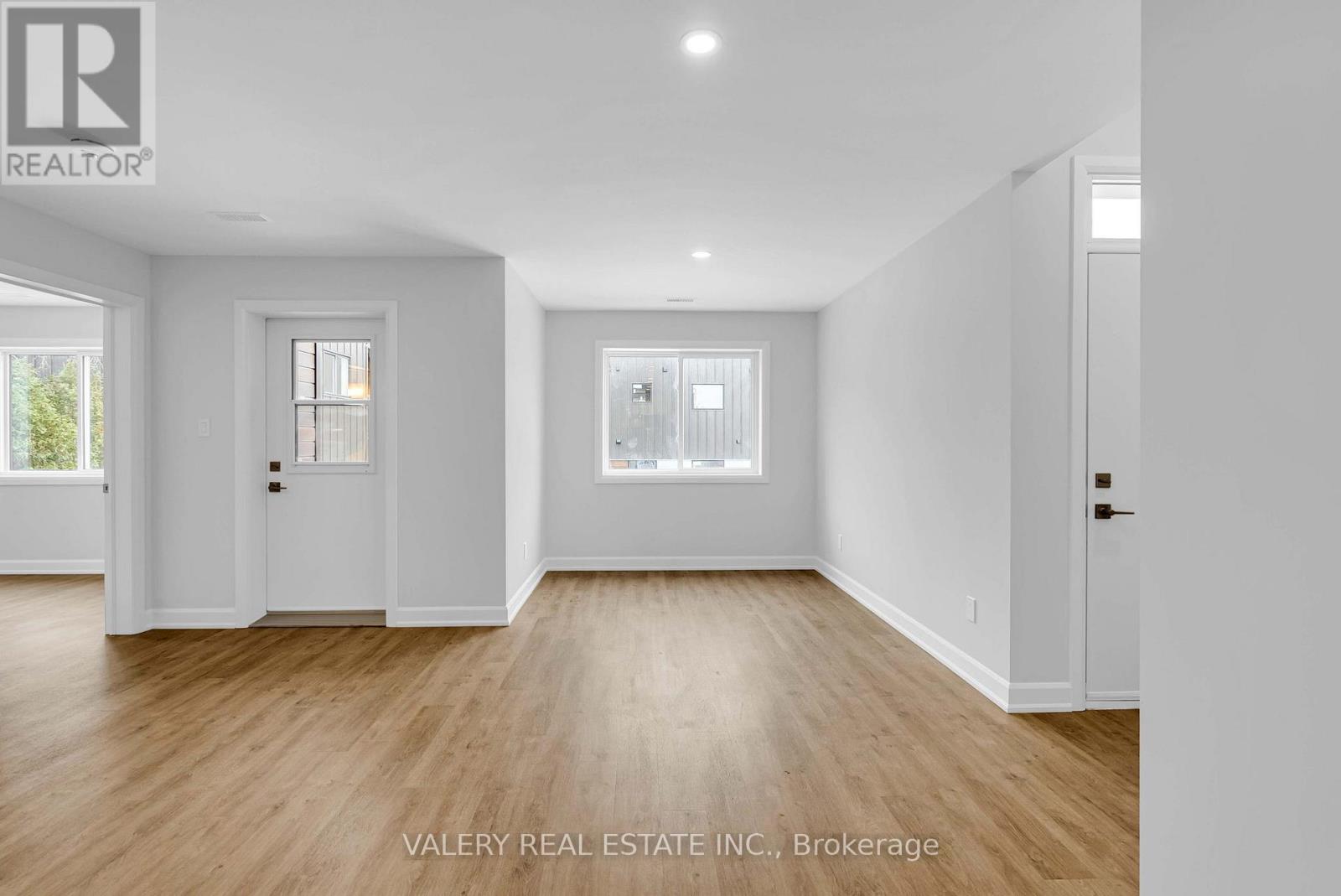 A spacious room with wooden floors and white walls.