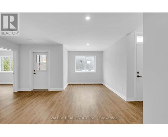 A spacious room with wooden floors and white walls.