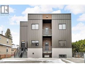 A modern two-story building with a flat roof and a balcony on the second floor.