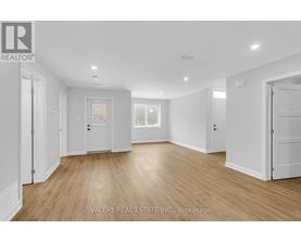A spacious room with wooden flooring and white walls.