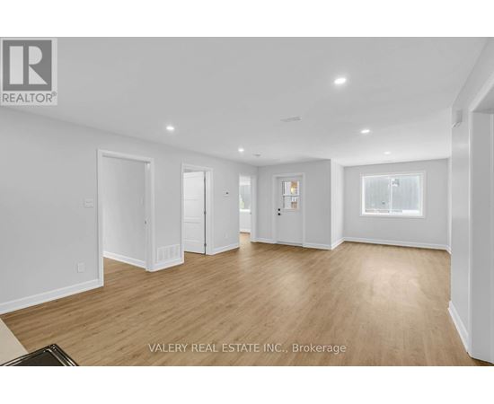 A spacious room with wooden flooring and white walls.