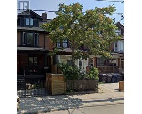 A tree in front of a house with a sign that says JOREALTY INC Brokerage.