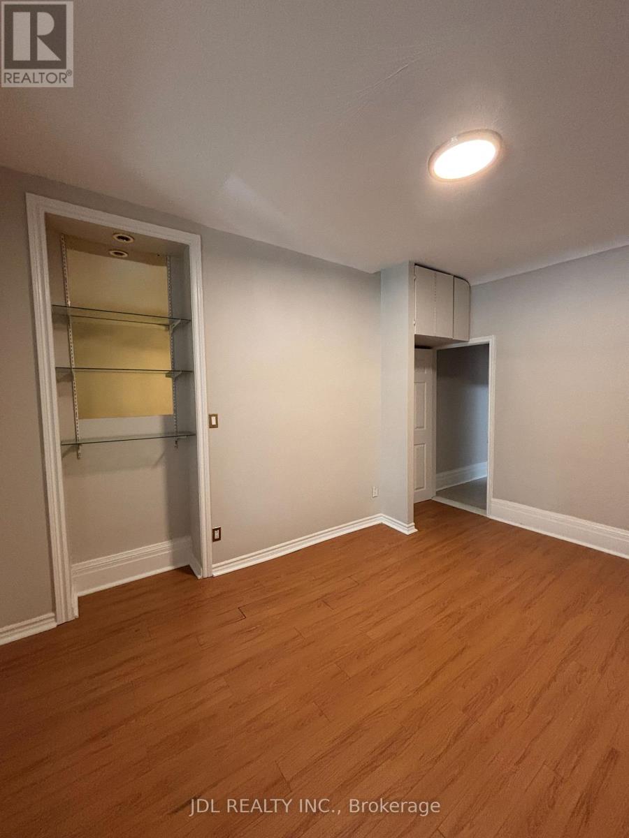 A room with wooden floors and white walls, with a door on the left and a closet on the right.