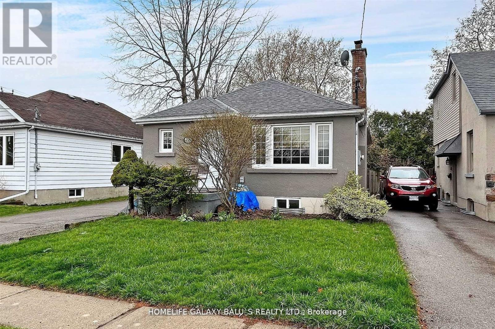 A house with a grey roof and a blue chair in front of it.