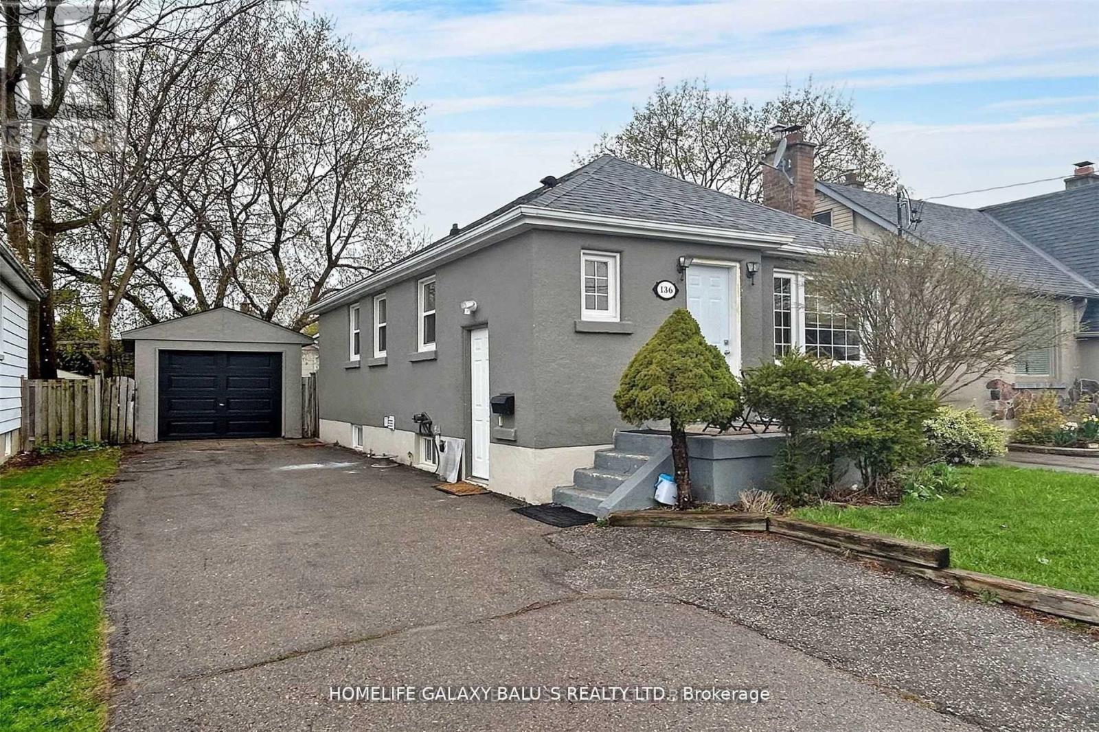 A grey house with a white door and a small garden in front.