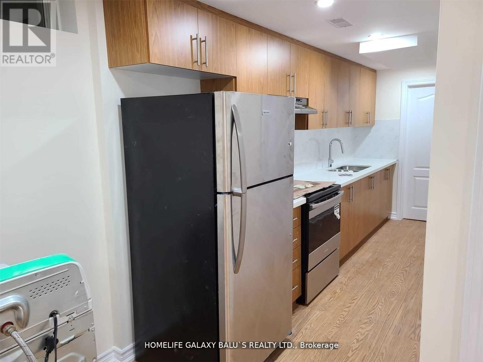 A kitchen with a black fridge and wooden cabinets.