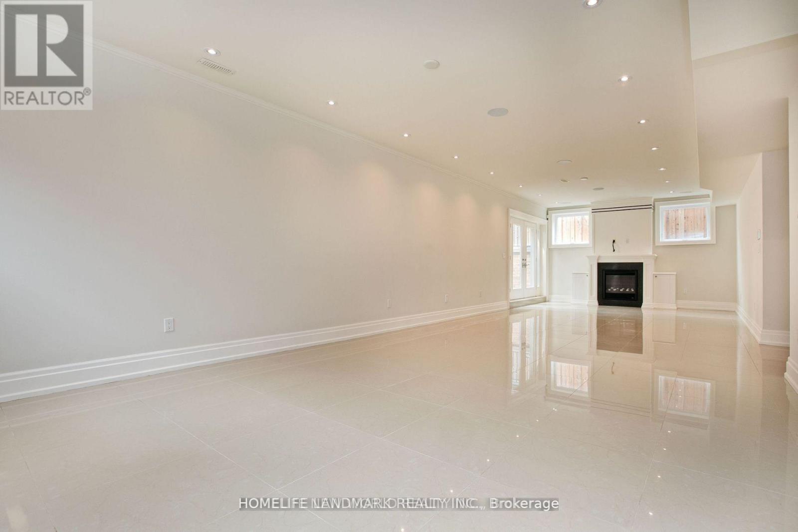 A spacious, empty room with a fireplace and a large mirror on the wall.