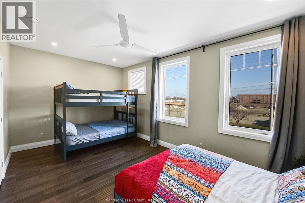 A bedroom with a bunk bed and a single bed with a colorful quilt on it.