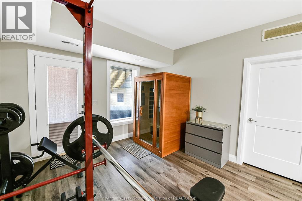 A gym room with a weightlifting rack, a bench, and a mirrored cabinet.