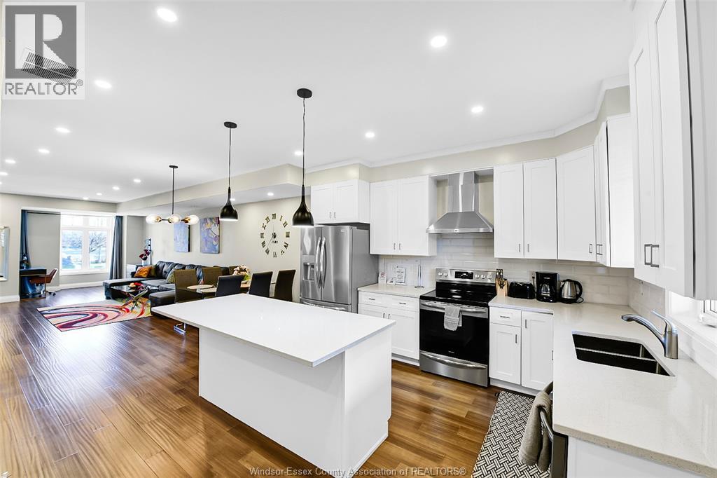 A modern kitchen with white cabinets and a wooden floor.