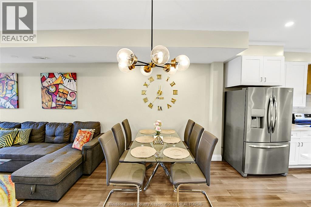 A modern dining room with a grey sofa, a glass table with plates and glasses on it, and a chandelier hanging from the ceiling.
